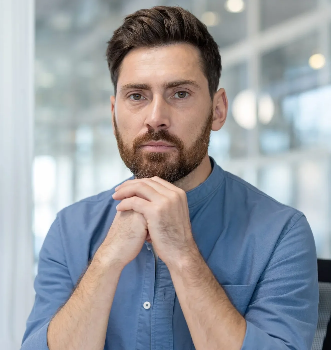 Man with hands clasped, looking thoughtful – online psychiatry in Oakland, CA